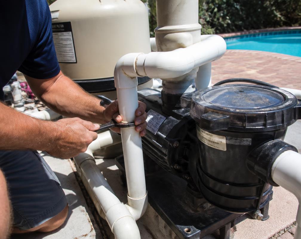 Technician repairing a pool pump and filter equipment pad